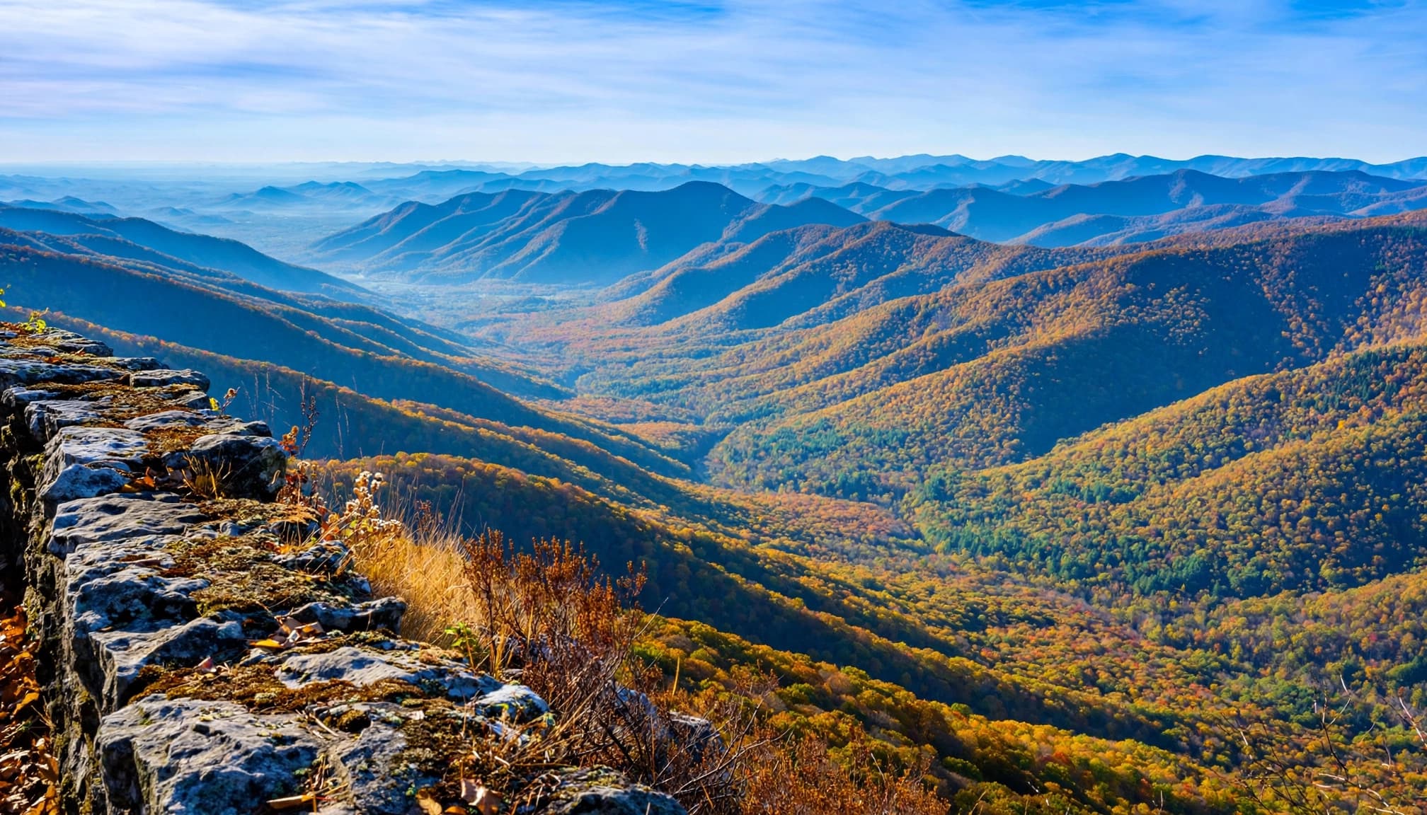 A scenic view of layered Appalachian mountains from a high stone overlook in autumn.